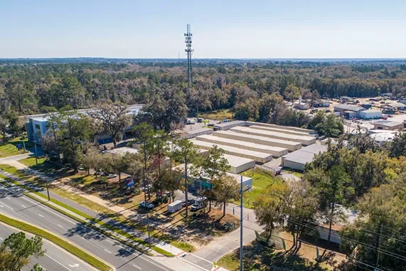 Aerial view of self storage facility near main road in wooded suburban area